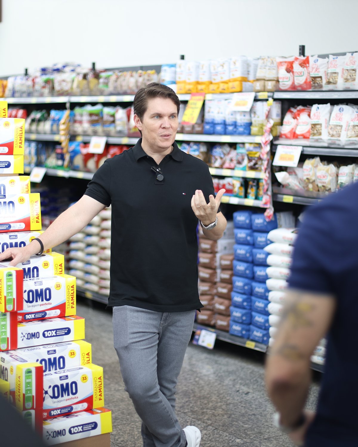 Pedro Della'Nora em pé num corredor do supermercado dele, explicando para um grupo de donos de supermercado